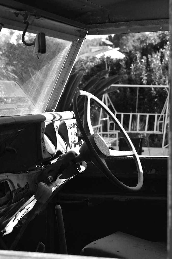 Steering wheel and dashboard of a vintage car in black and white.