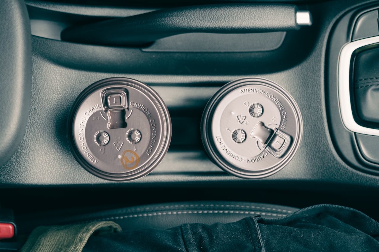 Car interior showing two disposable coffee cups in a holder, captured from above.